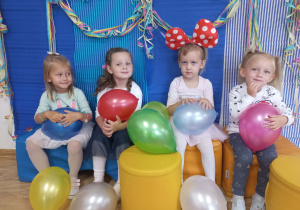 Dziewczynki z balonami pozują do zdjęcia grupowego.